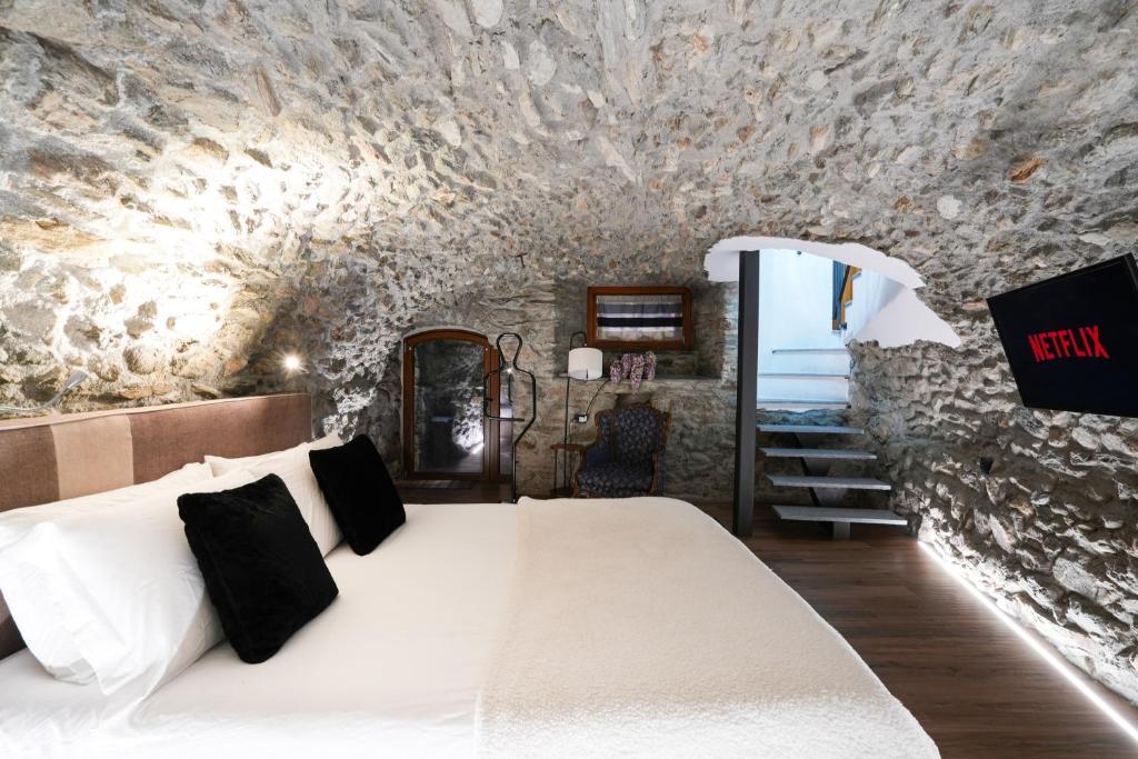 una camera da letto con un letto bianco in un muro di pietra di Roisan Apartment a Castello