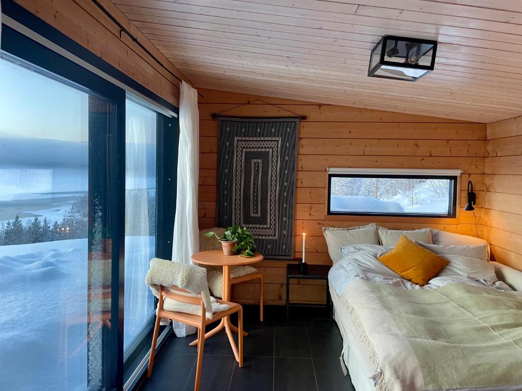 een slaapkamer met een bed, een tafel en een raam bij Luxury Arctic Cabin in Øverbygd