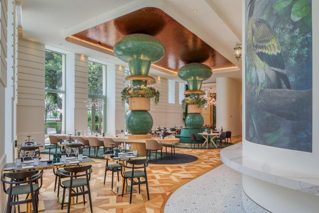 a restaurant with tables and chairs and large vases at Kimpton BEM Budapest by IHG in Budapest