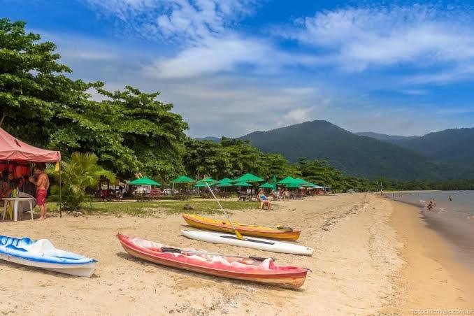 a group of boats on a beach with green umbrellas at Casa a 100 metros da praia do Jabaquara in Paraty