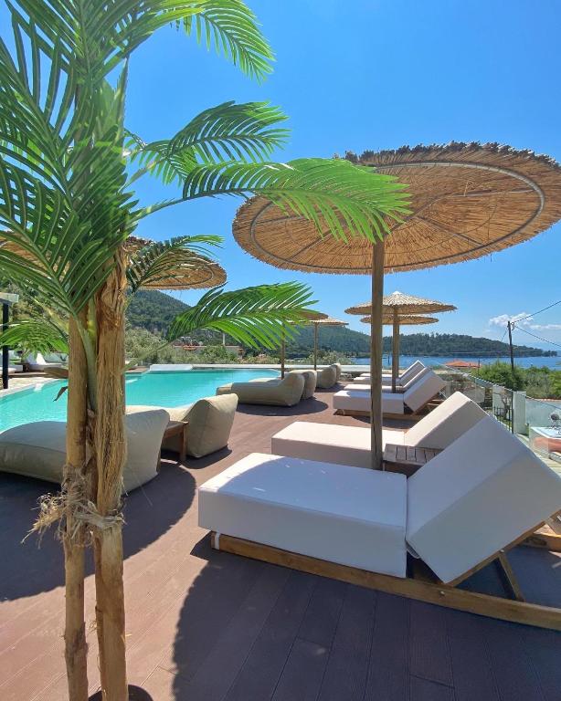 a resort patio with white furniture and a palm tree at Panormos Beach Hotel Skopelos in Panormos Skopelos