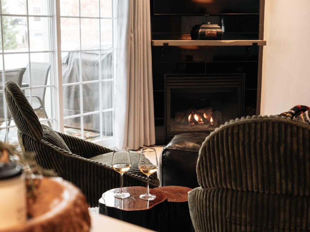 Una sala de estar con dos sillas y una mesa con copas de vino. en Mountain Escape Ski-In Ski-Out Laurentians, en Saint-Faustin