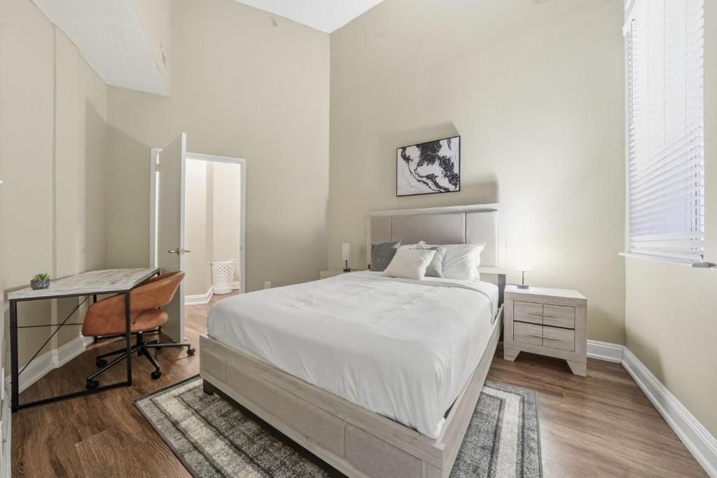 een witte slaapkamer met een bed, een bureau en een stoel bij Modern 1BR perfect for extended visits in New Haven