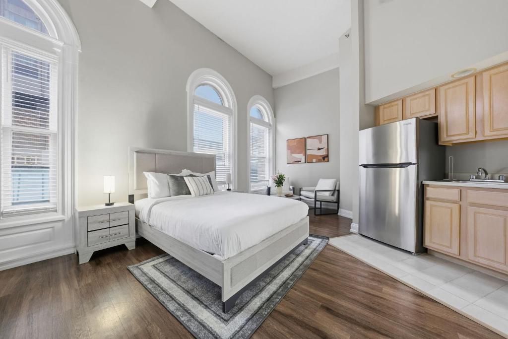 a white bedroom with a bed and a kitchen at Relaxing studio perfect for extended visits in New Haven