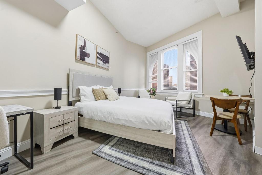a white bedroom with a bed and a desk at Homey studio perfect for long-term guests in New Haven