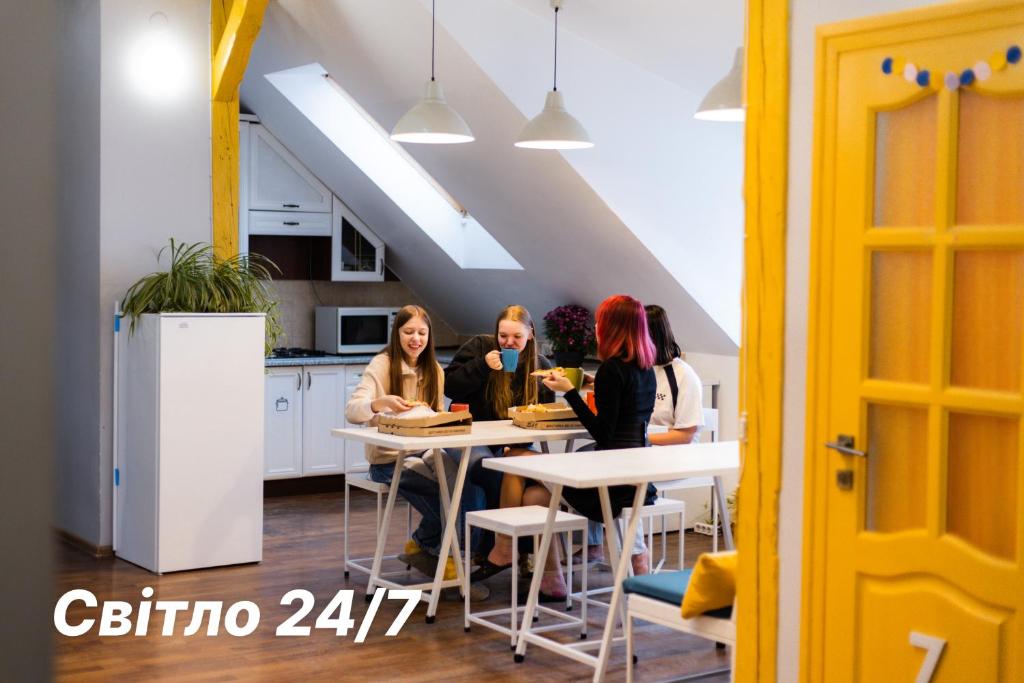 un grupo de personas sentadas en una mesa en una cocina en Open Home Hostel, en Leópolis