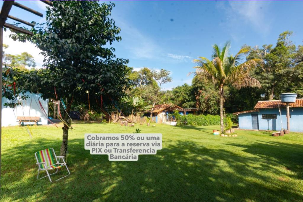 Pousada, Hostel e Camping Jardim da Mata في شابادا دوس غيماريش: ساحة بها شجرة ولافتة في العشب