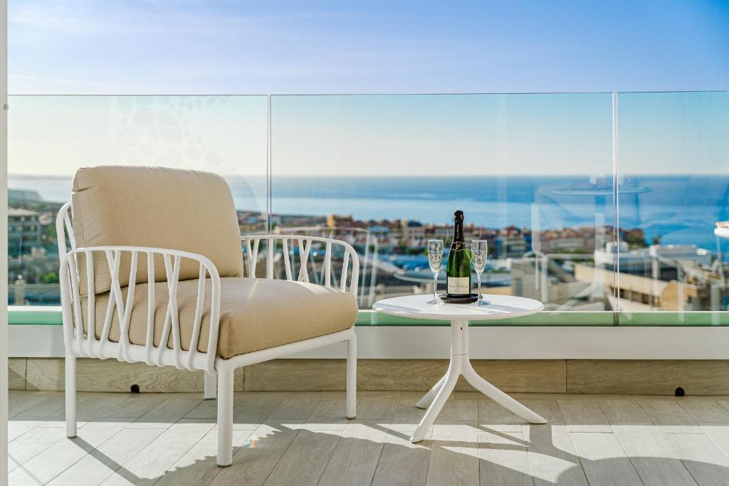 a white chair and a table with a bottle of wine at Sundream Escape - Penthouse with ocean view, airco, heated pool in Adeje