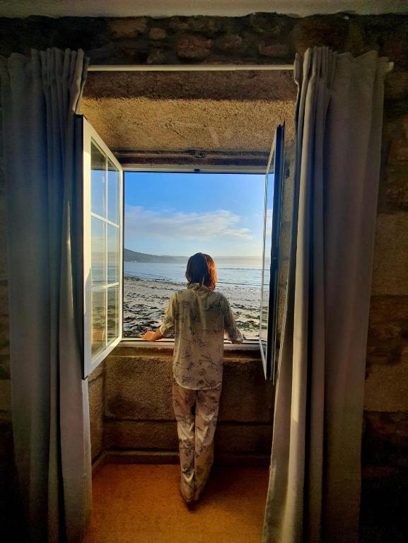 a woman looking out of a window at the ocean at La Casa de Ana en Fisterra in Fisterra
