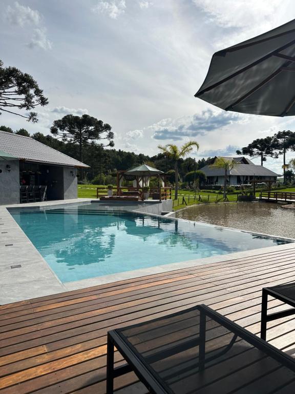 una piscina con una terraza de madera y una sombrilla en Morada Das Grimpas, en Palmeira