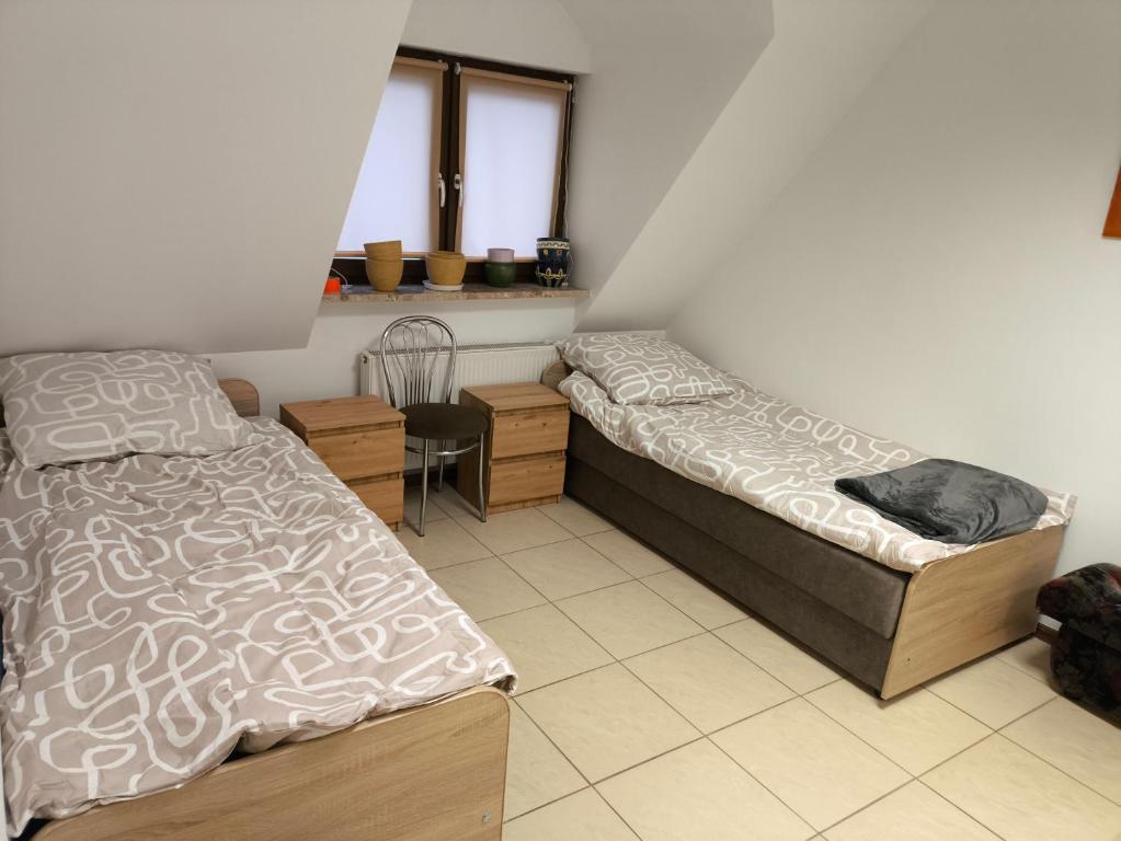 a bedroom with two beds and a desk and a chair at Noclegi w mieście in Kozienice