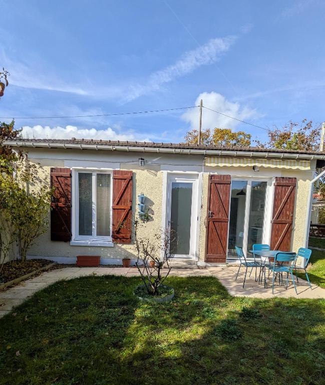 une maison avec deux portes, une table et des chaises dans l'établissement Maison Le cottage, à Crosne