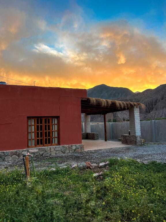 a red building with a sunset in the background at Wayra del Cerro in Purmamarca