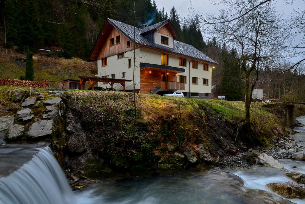 een huis op een heuvel naast een rivier bij Apartmaji nad potokom in Železniki