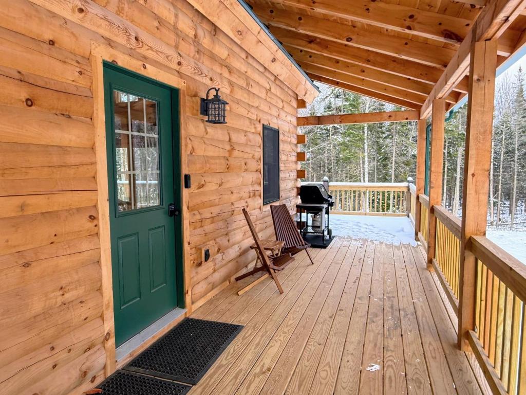a cabin with a green door and a grill on a deck at 2S New log cabin in Bethlehem - privacy, firepit, great location! in Bethlehem