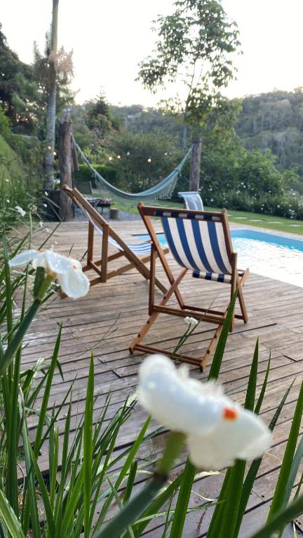 Eine Terrasse mit einem Stuhl und einer Hängematte in der Nähe eines Pools in der Unterkunft Casa da Rota dos Ipês in Domingos Martins