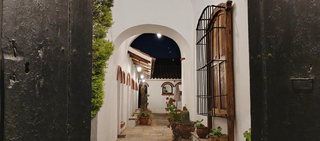 Un callejón con paredes blancas y un arco con plantas. en Hostal Colonial Potosi, en Potosí