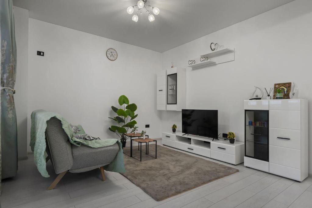 a white living room with a chair and a television at Apartament Militari Residence in Dudu