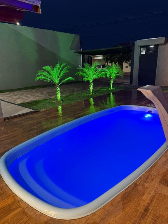 a blue swimming pool in a yard with palm trees at Recanto Neri & Neide in Olímpia