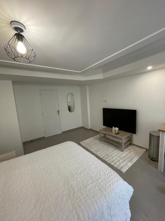 Studio proche de Paris في Valenton: غرفة نوم مع سرير وتلفزيون بشاشة مسطحة