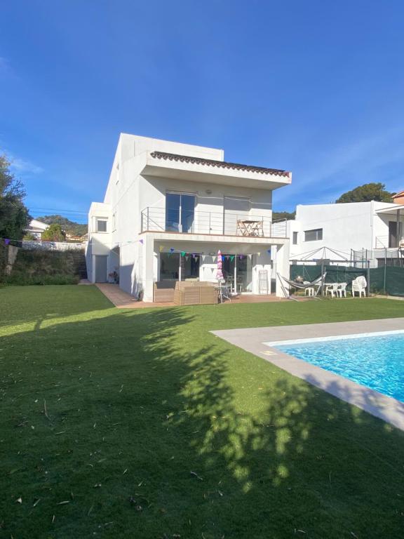 a white house with a swimming pool in front of it at Stunning Villa 25' from Barcelona in Las Canteras