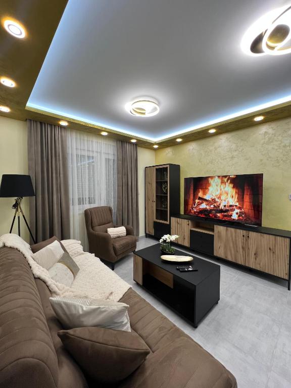 a living room with a couch and a large tv at Golden Time SM Apartman in Sremska Mitrovica
