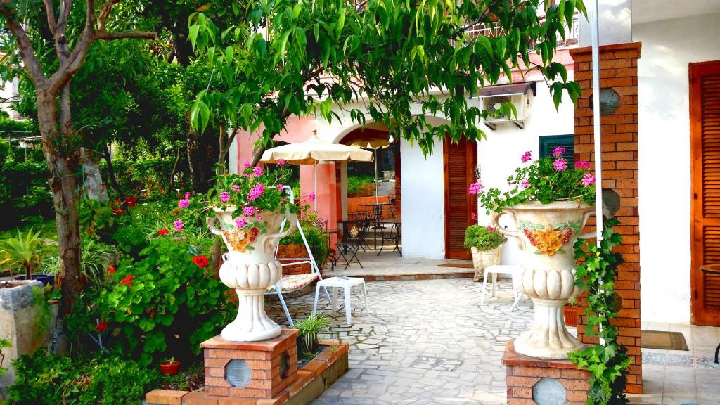 un patio con 2 jarrones blancos llenos de flores en Nonna Vincenza en Maratea