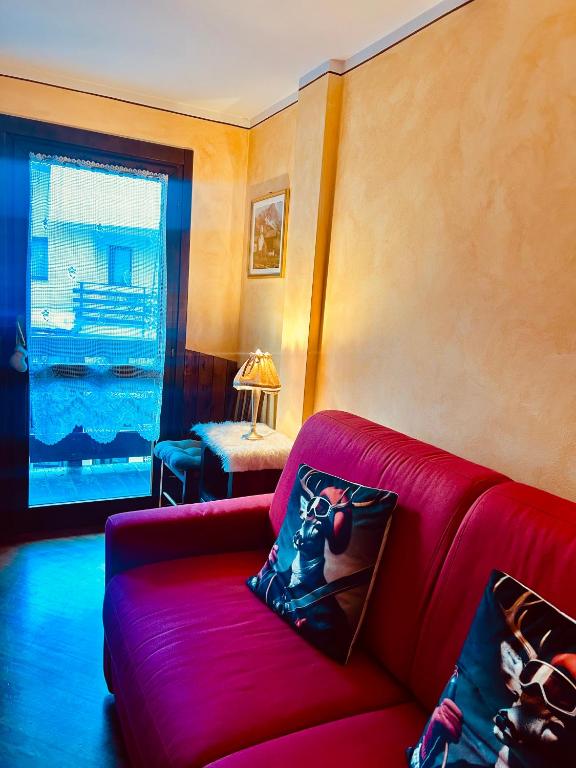 a living room with a red couch and a window at Charme a Cervinia Downtown Ski in-Ski out in Breuil-Cervinia
