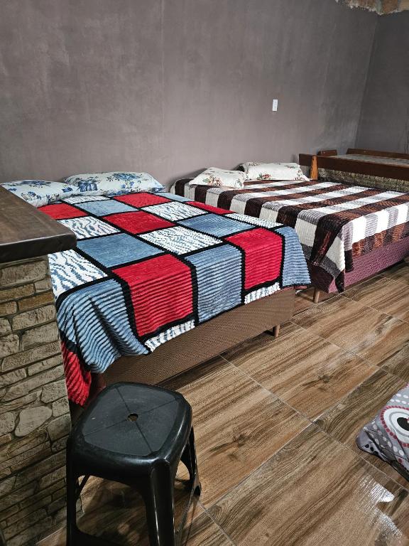 two beds in a room with a chair and a table at Recanto do Descanso in São Gabriel
