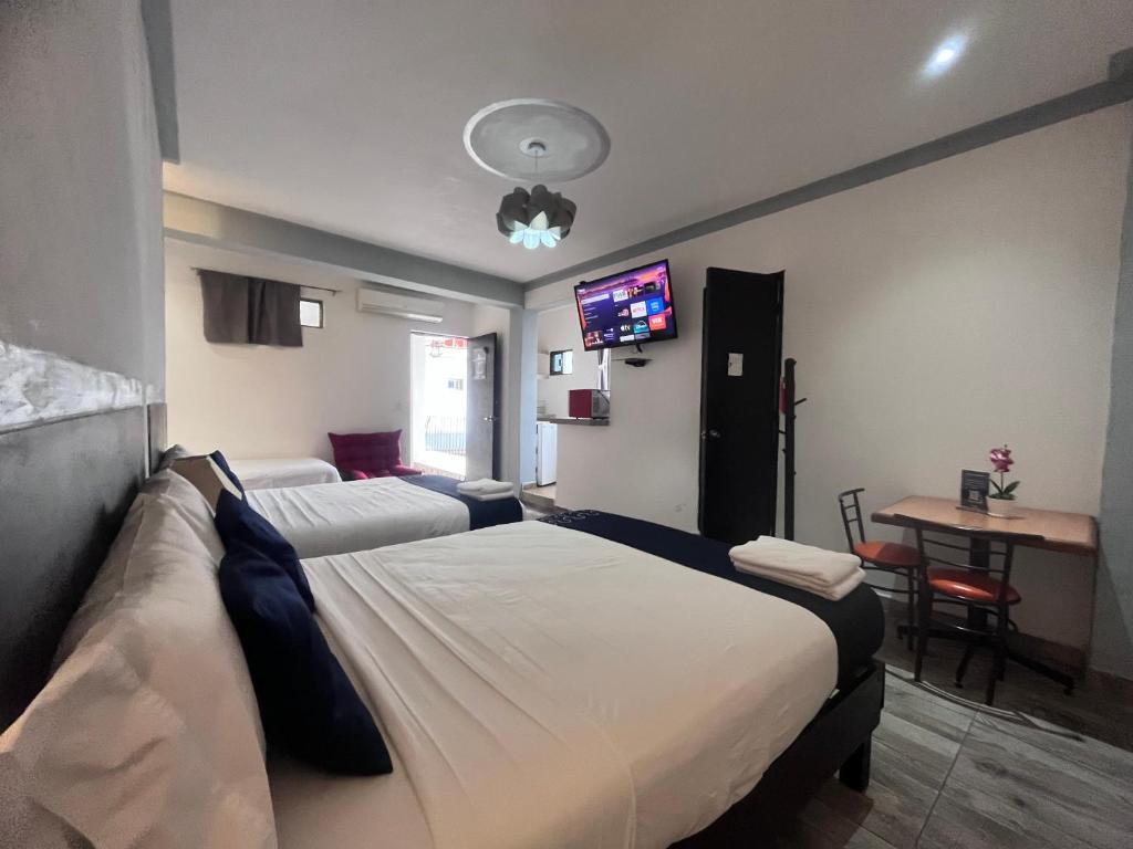 a hotel room with two beds and a flat screen tv at Hotel Gandag in Orizaba