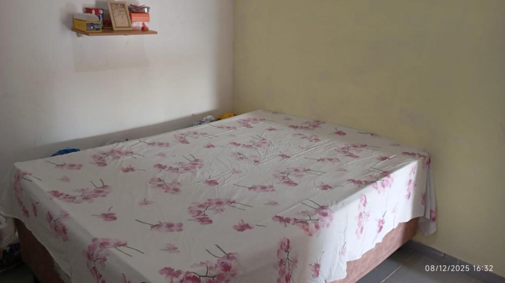 a bedroom with a bed with a pink floral sheet at Casa temporada Tucano in Vera Cruz de Itaparica