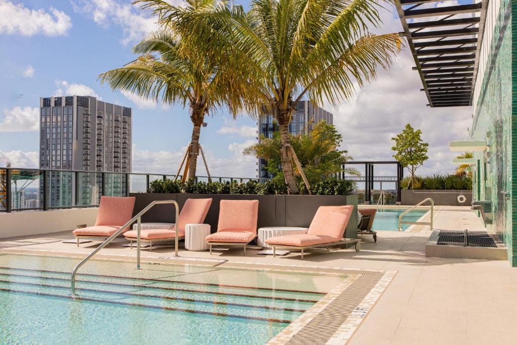 a pool with chairs and palm trees on a building at The Crosby Miami Worldcenter in Miami