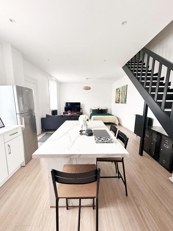 a kitchen and living room with a white table and chairs at Grand Studio WiFi rapide RER B in Sevran