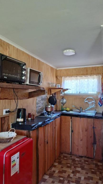 cocina con armarios de madera y nevera roja en Paraíso Rustico 3, en Curacautín