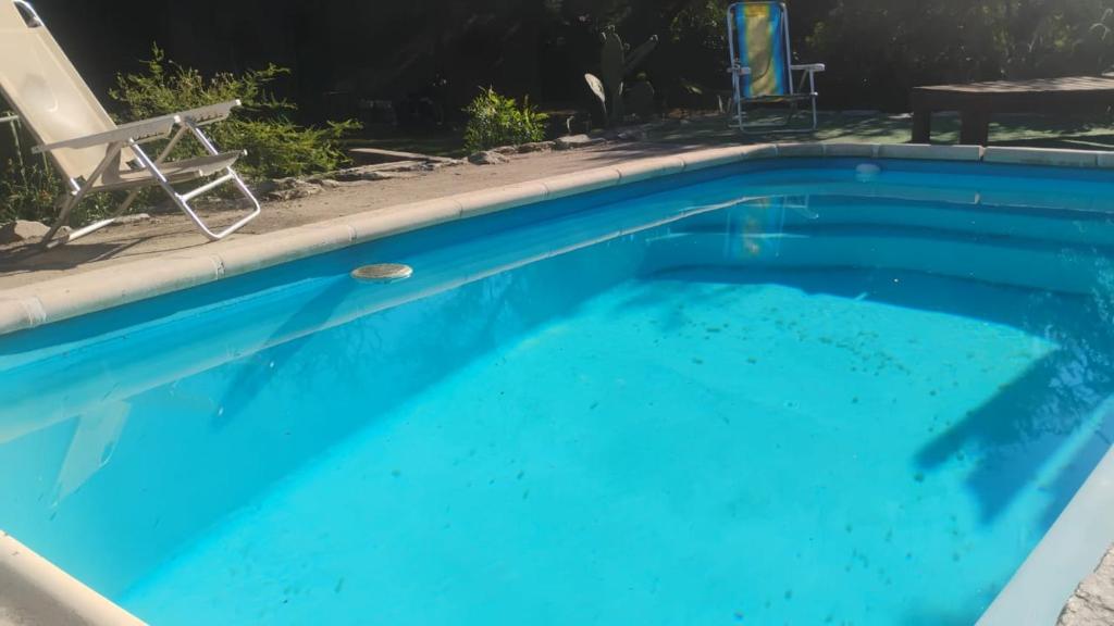 ein blauer Swimmingpool mit einem Stuhl und einer Chaiselongue in der Unterkunft CASA SAMARANA Alta Gracia in Alta Gracia