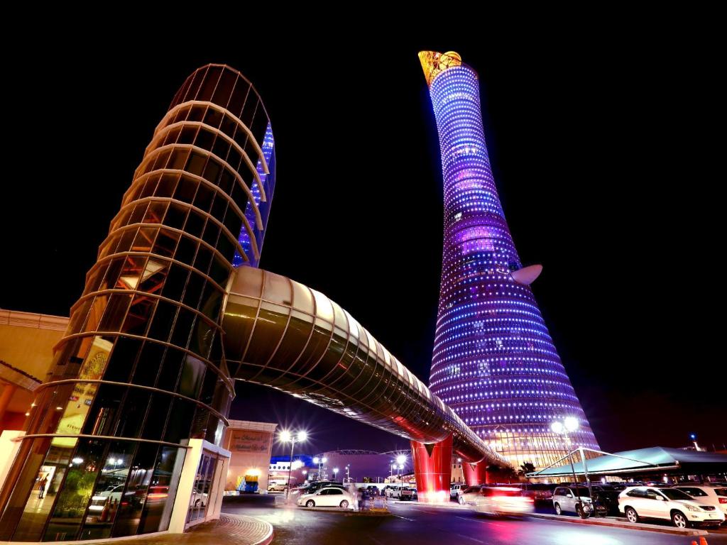 two tall buildings are lit up in purple at The Torch Doha in Doha
