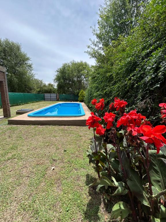 una piscina con fiori rossi nel cortile di Casa quinta a Estación Norte