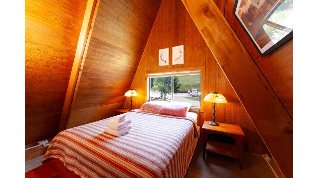 a small attic bedroom with a bed and a window at Claim Jumper A-Frame 2 - On The River - WiFi - Cable - Wood Burning Fireplace in Red River