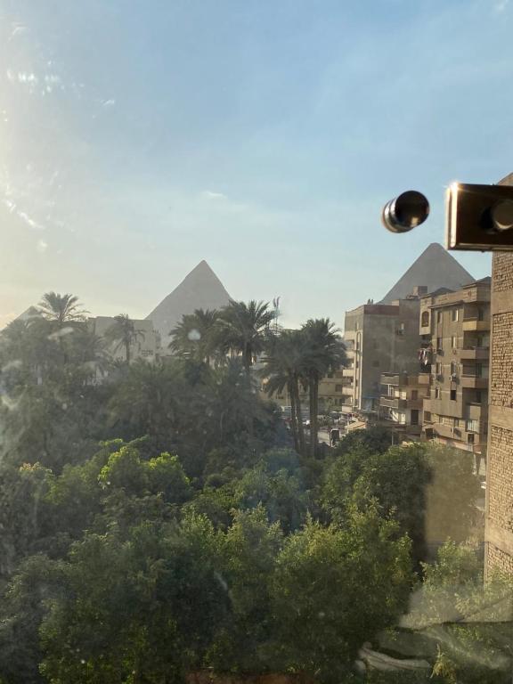 Una vista de las pirámides desde una ciudad con árboles y edificios. en Good Nights Pyramids Hotel, en El Cairo