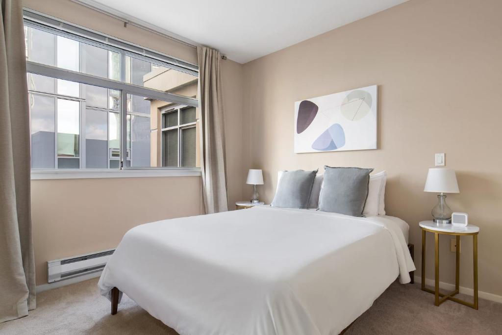 a white bedroom with a large bed and a window at Kasa Bellevue Seattle in Bellevue