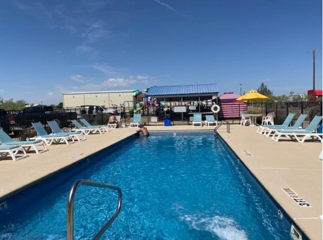 a swimming pool with chairs and a person in the water at Mesquite Oasis Lodging in Odessa