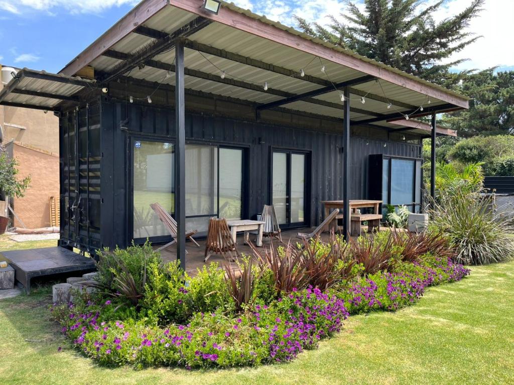 una casa nera con un tavolo, delle panche e dei fiori di elcontainerdeacantilados a Mar del Plata