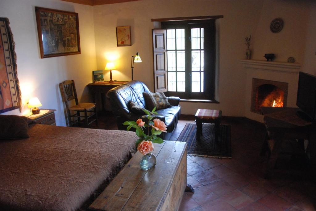 a living room with a couch and a table and a fireplace at Cortijo Prado Toro in Pitres