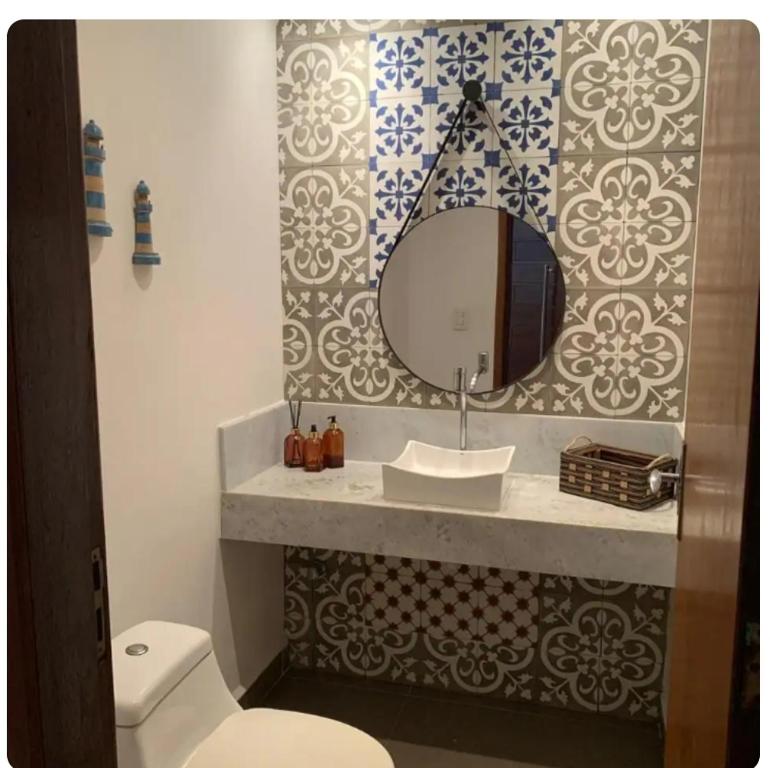 a bathroom with a white toilet and a mirror at Casa de Praia in Bertioga