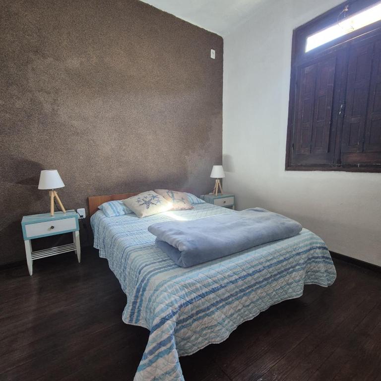 una cama en una habitación con dos mesas y dos lámparas en Casa en el centro de Piriapolis a 1 cuadra de la playa, en Piriápolis