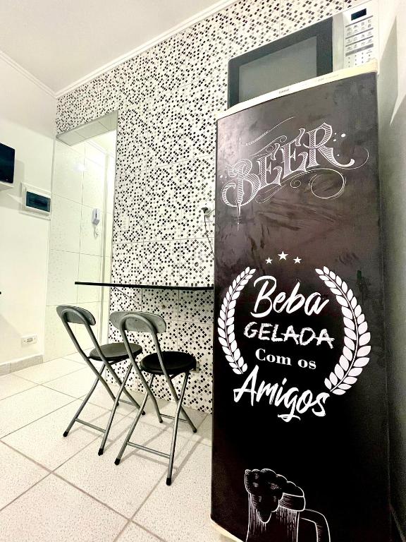 a restaurant with two chairs and a sign on a wall at Brisa do mar Kitinete in São Vicente
