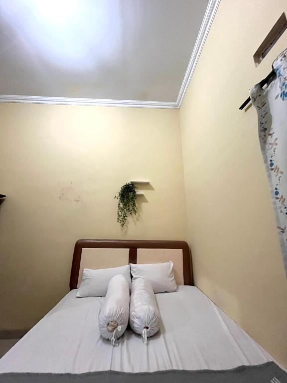 a bedroom with a bed with two pillows on it at Raphi house in Yogyakarta