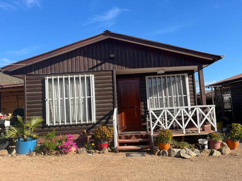 Una pequeña casa de madera con dos ventanas y plantas en macetas. en Clocabana, en Totoralillo