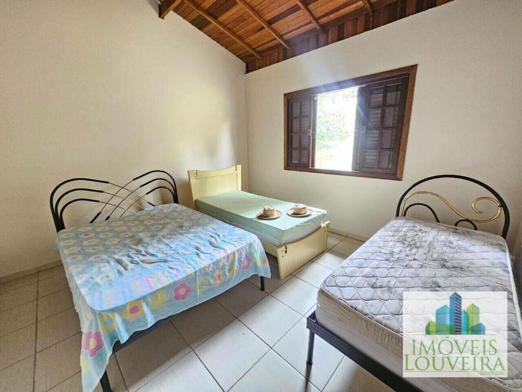 een kamer met twee bedden, een tafel en een raam bij Chácara com 3 dormitórios in Louveira