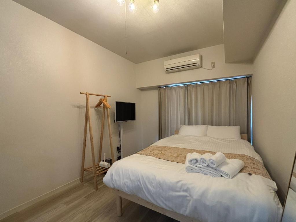 a bedroom with a bed with towels on it at P-Stay広島富士見町302 in Hiroshima